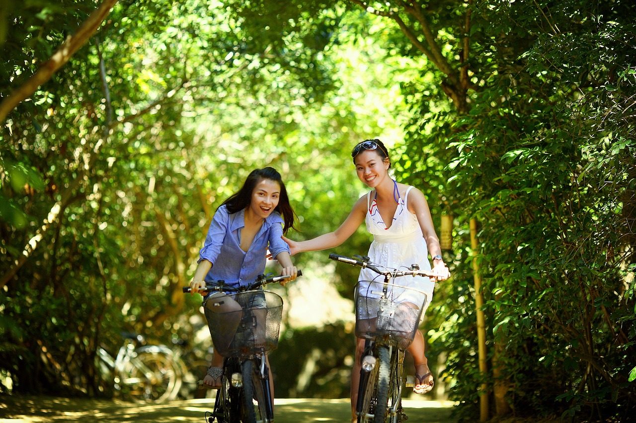Two people riding through a forest on bicycles